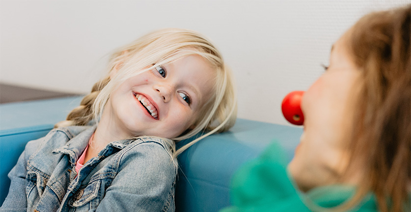 meisje dat lacht naar een clini clown dankzij een goed doel kerstpakket